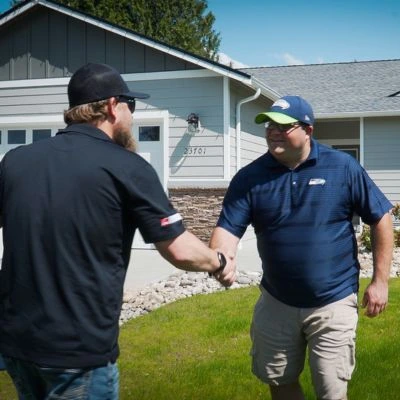 An S&S Roofing team member shaking hands with a satisfied homeowner.