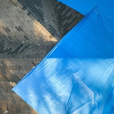 Aerial view of a tarp on a  damaged, leaking roof.