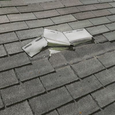 damaged roof showing shingles that have been torn up by wind damage